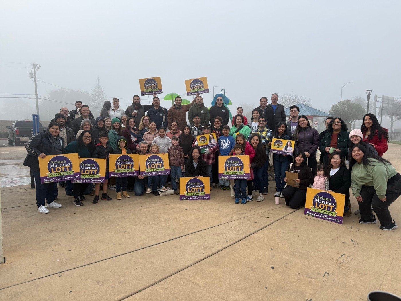 A large group of campaign volunteers standing outdoors together holding Ariana Martinez Lott yard signs